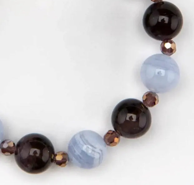 A row of gold, dark purple and light blue beads on a white background.