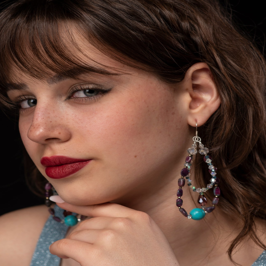 Close-up of a woman wearing colorful earrings with a dark background