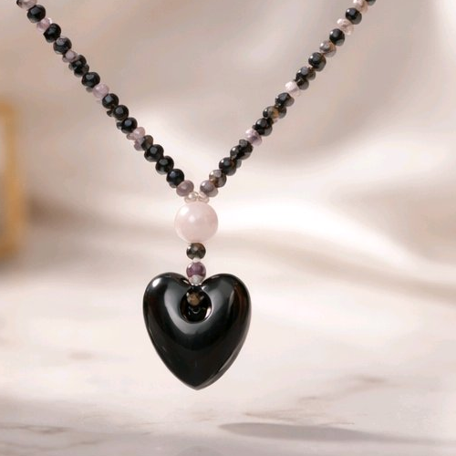 Necklace with a heart shape against a light pink background.