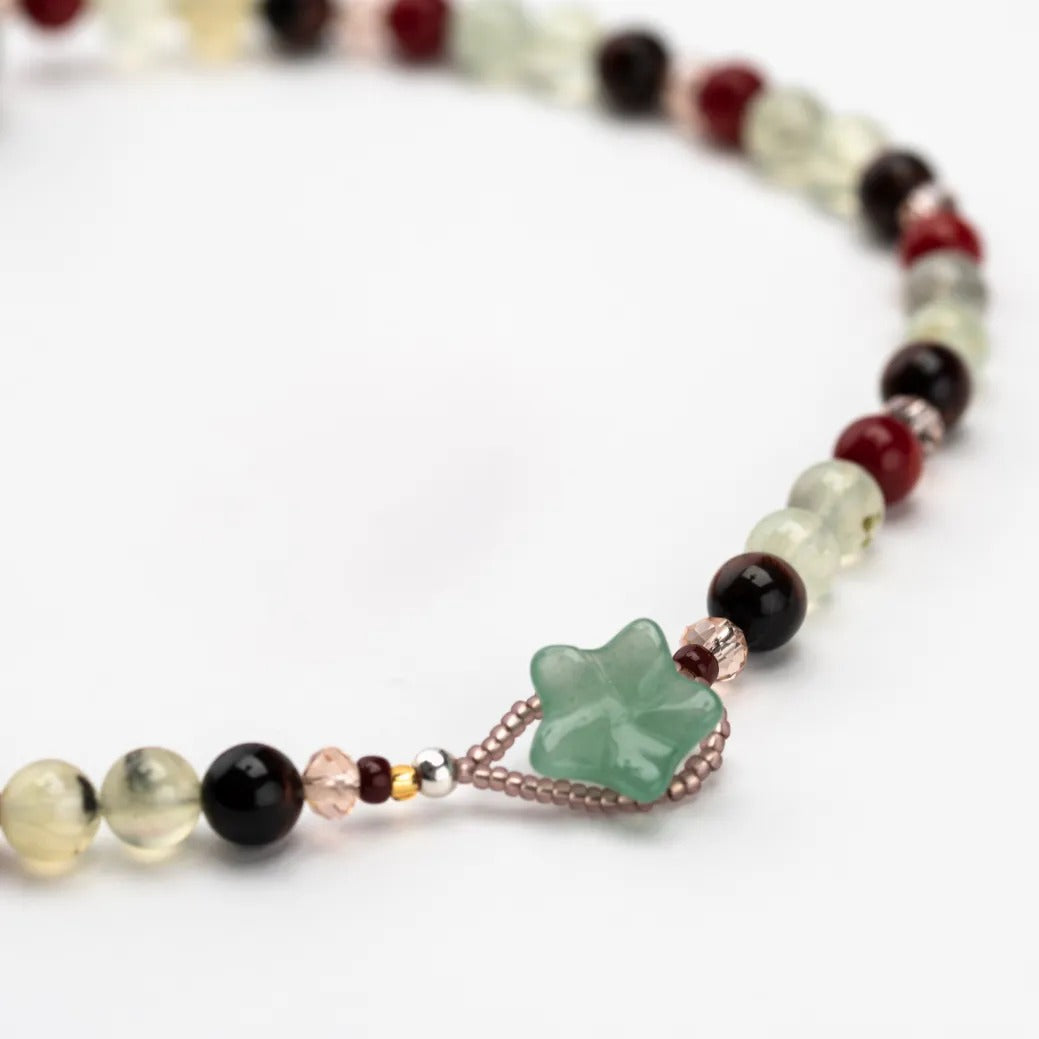A green crystal button fastening with other colourful beads on a white background.