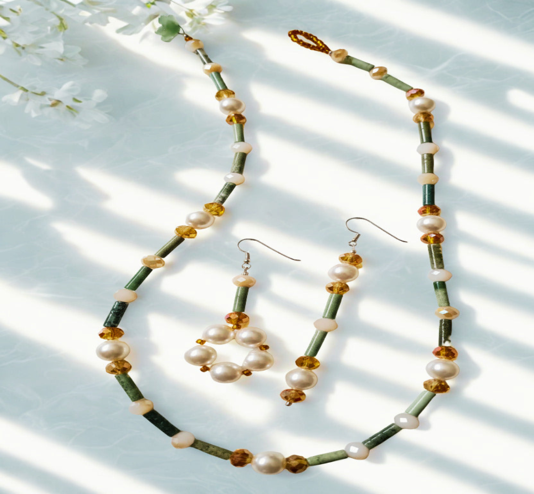 Beaded necklace and earrings set with green, brown, and white beads on a light background.
