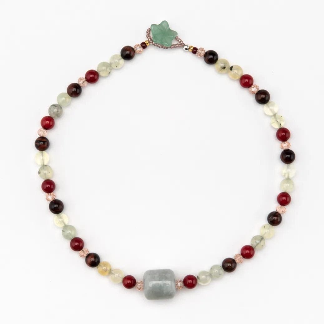A multicolored semi-precious bead necklace with a green aventurine flower button, featuring various colored beads including red coral, tiger's eye, and jade, on a white background.