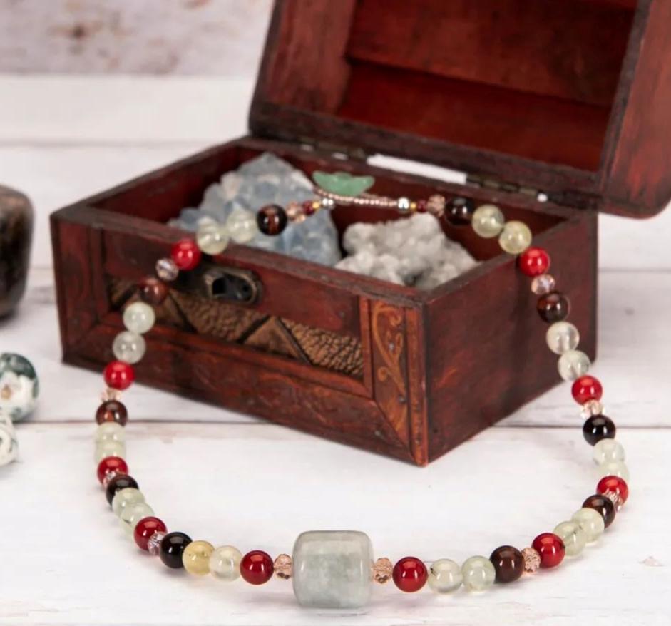 A necklace on a wooden chest and a white table.